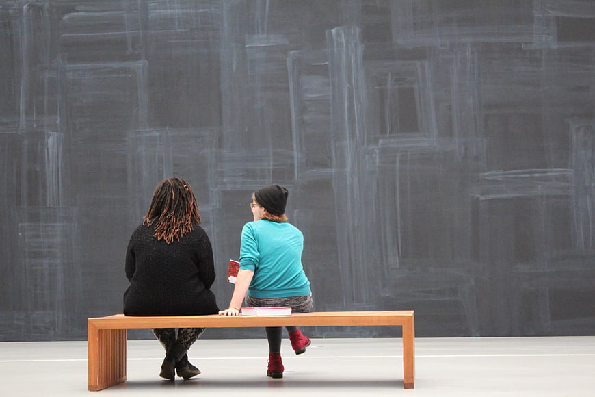 Two Women Viewing Abstract Artwork in Modern Museum Gallery
