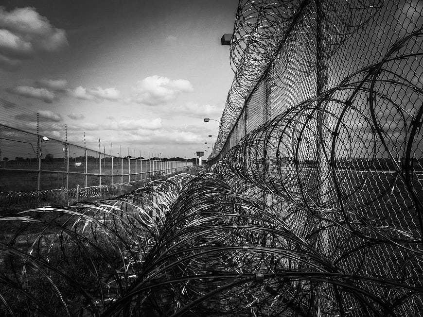 Black and white razor wire prison fence perspective