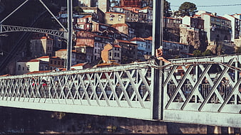 Woman sitting on metal bridge railing with cityscape background