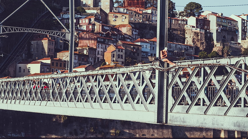 Woman sitting on metal bridge railing with cityscape background