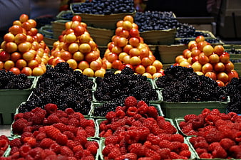 Fresh berries and plums arranged in market baskets