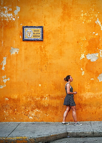 Woman walking past vibrant orange wall with church sign