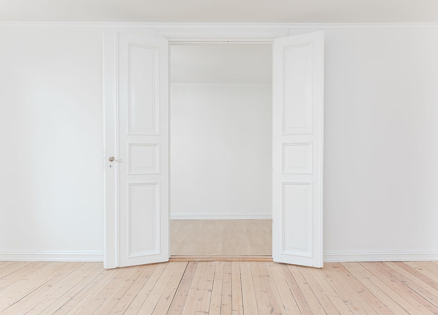 Minimalist white interior with open double doors and wooden floor