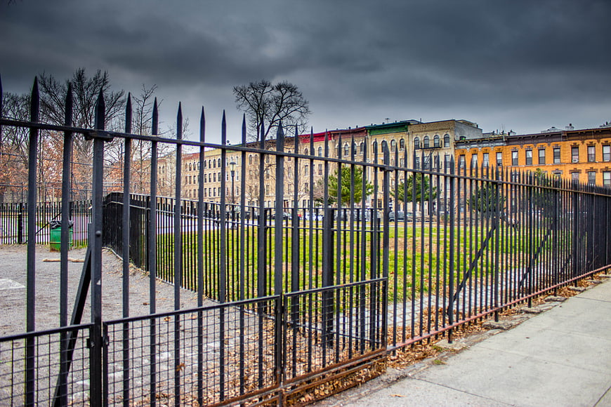 Urban Park Fence with Stormy Sky and City Buildings