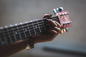 Close-up of hand playing acoustic guitar with bracelets
