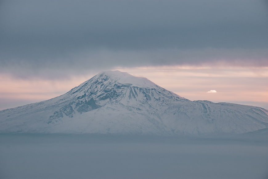 Snow-Capped Mountain Peak Above Clouds at Dusk