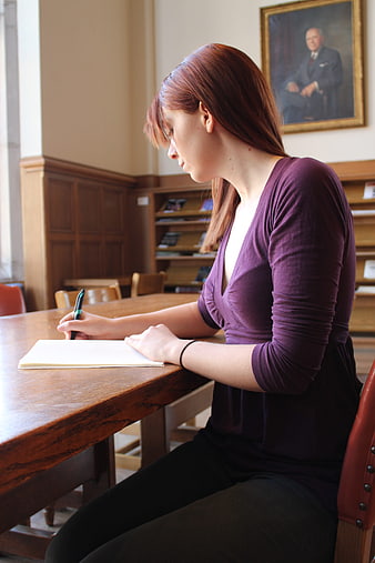 Young woman studying at wooden table in library