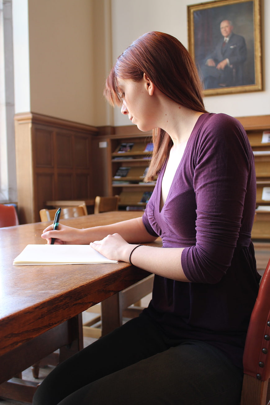 Young woman studying at wooden table in library