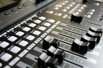 Close-up of professional audio mixing console with sliders and buttons