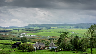 Scenic rural valley landscape with stone farmhouses and green fields