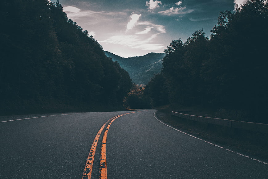 Winding Mountain Road Through Forest at Dusk