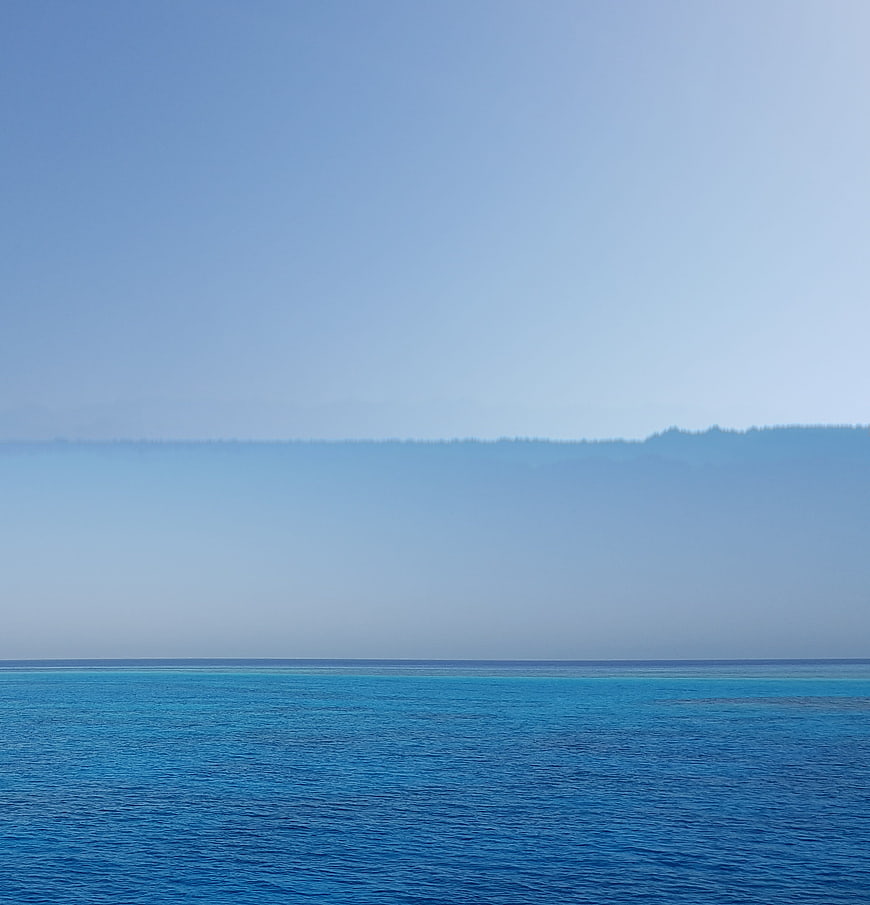 Serene Blue Ocean View with Distant Hazy Mountains