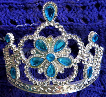 Silver tiara with blue rhinestones on blue fabric