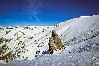 Snowy Mountain Landscape with Rocky Outcrop and Blue Sky
