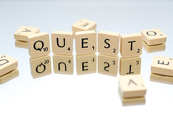 Scrabble Tiles Spelling Quest on White Background