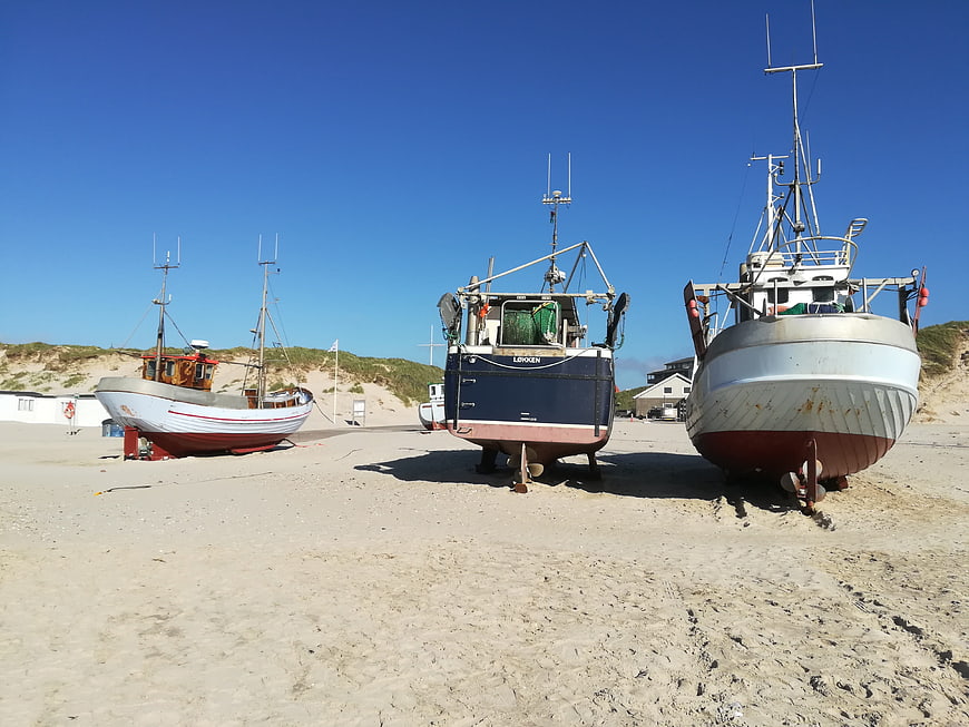 Fishing boats resting on sandy beach under blue sky