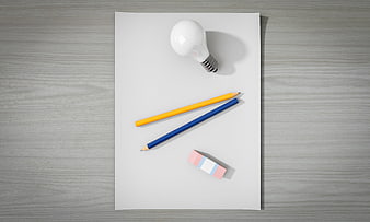 Top view of light bulb, pencils, and eraser on white paper