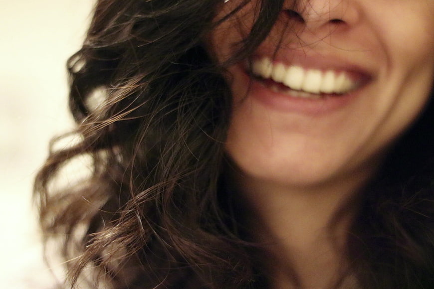 Close-up of a woman laughing with hair covering face