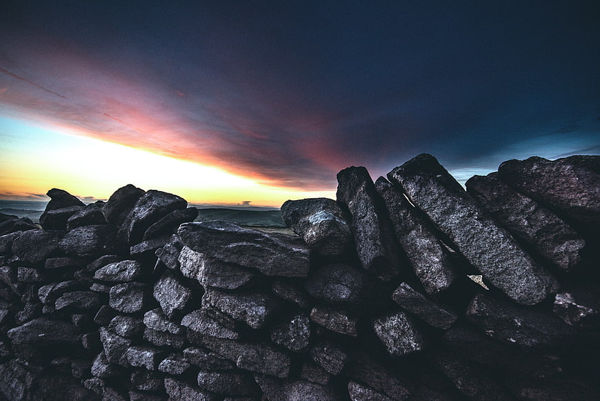 Dramatic Sunset Sky Over Dark Stone Wall Landscape