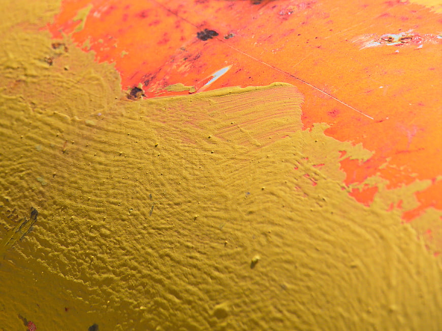 Close-up of distressed yellow and orange painted metal texture
