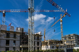 Construction site with multiple cranes against blue sky