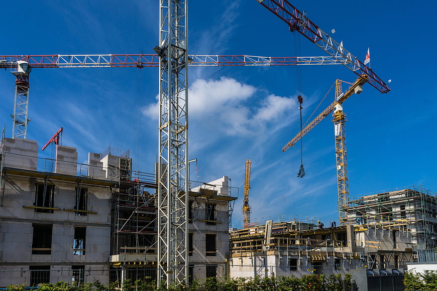 Construction site with multiple cranes against blue sky