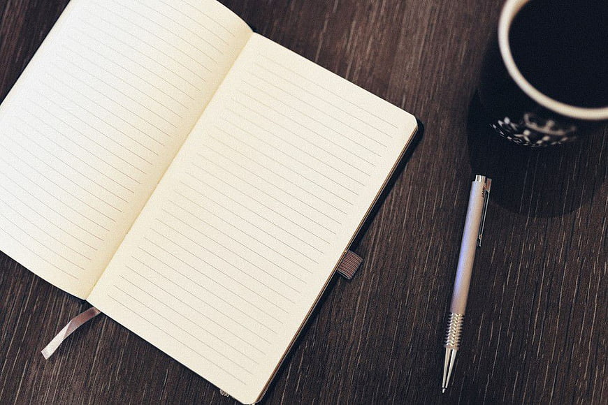 Open Notebook, Pen, and Coffee on Dark Wood Desk