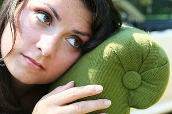 Close-up portrait of woman resting head on green cushion