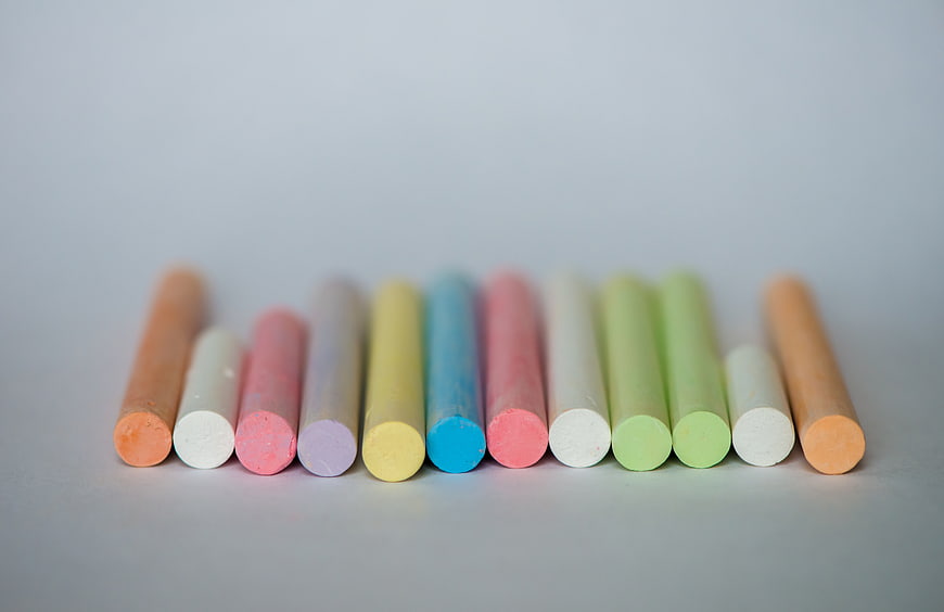 Row of colorful chalk sticks on a light gray background