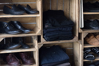 Vintage leather shoes and folded dark jeans on rustic wooden shelves