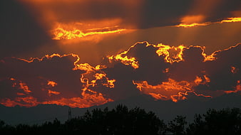 Dramatic orange sunset clouds over mountain silhouette