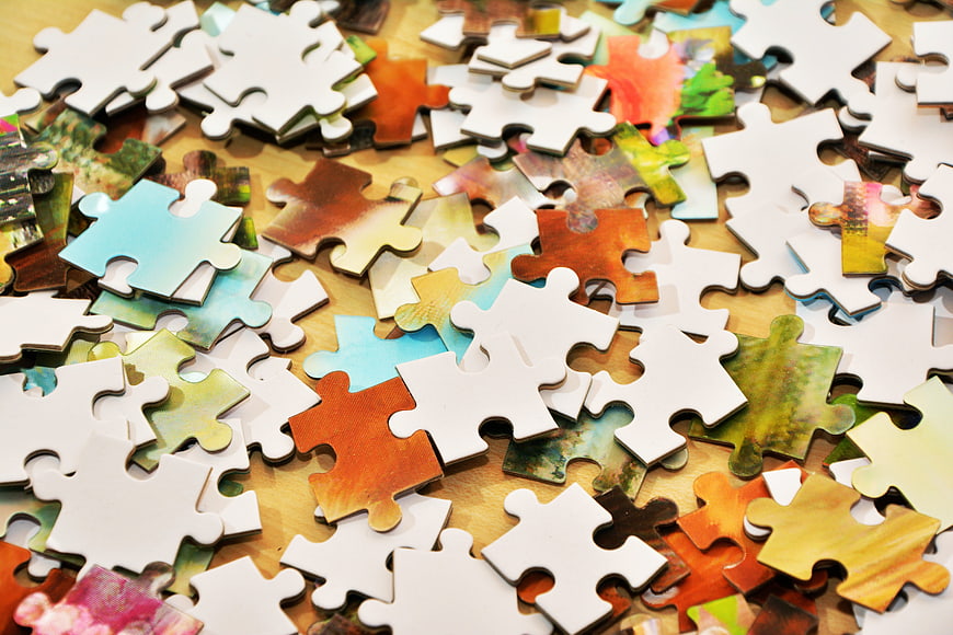 Scattered Jigsaw Puzzle Pieces on Wooden Table