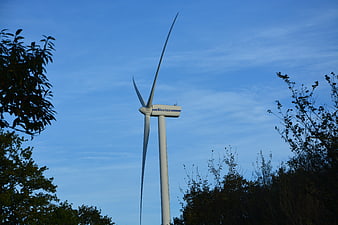 White Vestas wind turbine against blue sky with trees