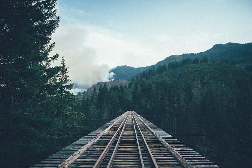 Wooden Railway Bridge in Forest with Distant Smoke