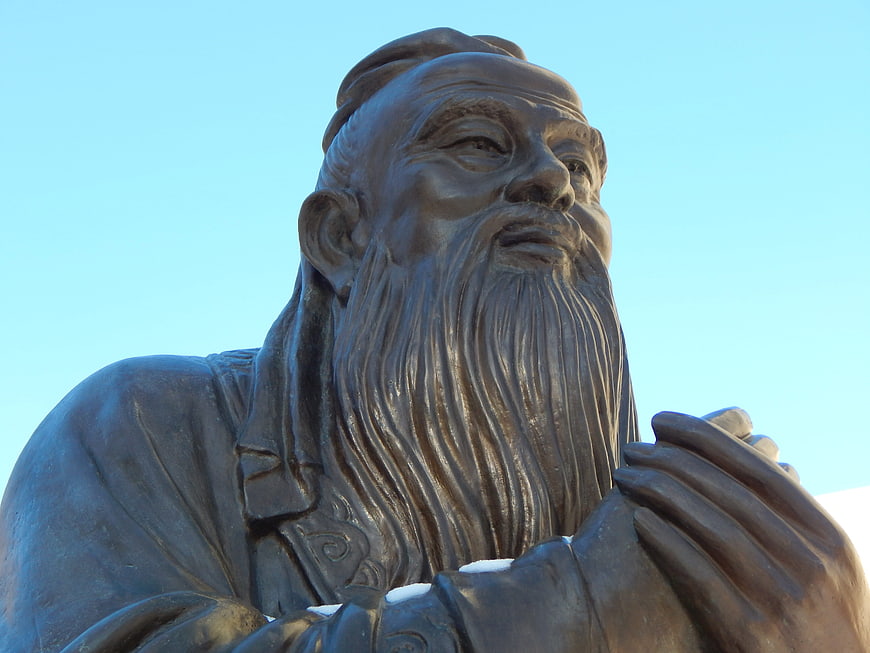 Close-up of a bronze Confucius statue against a clear blue sky