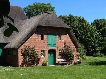 Traditional Red Brick House With Thatched Roof In Rural Northern Germany