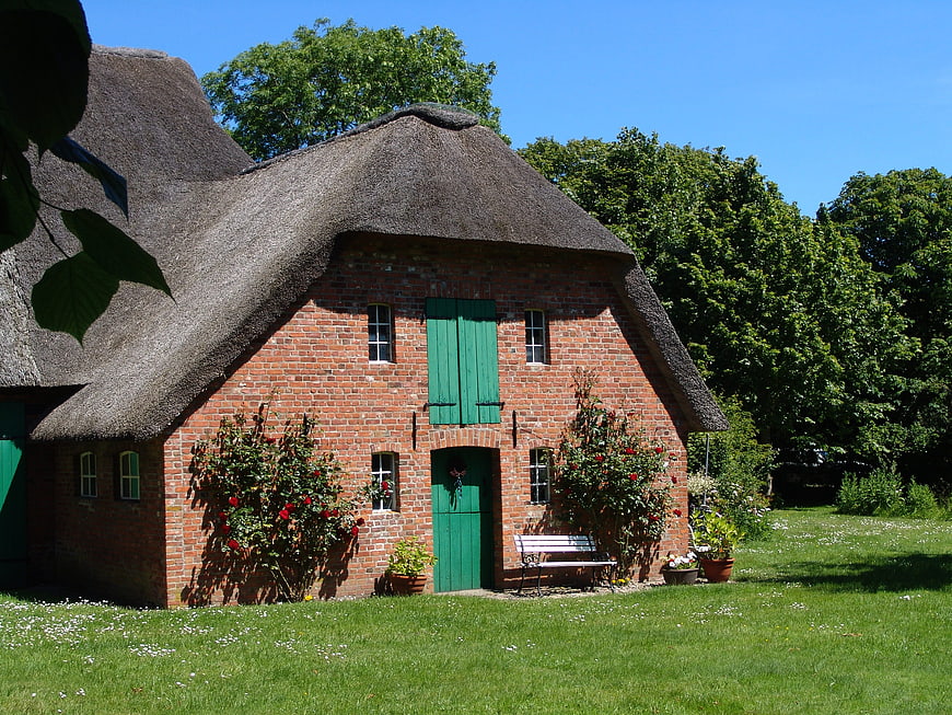 Traditional Red Brick House With Thatched Roof In Rural Northern Germany