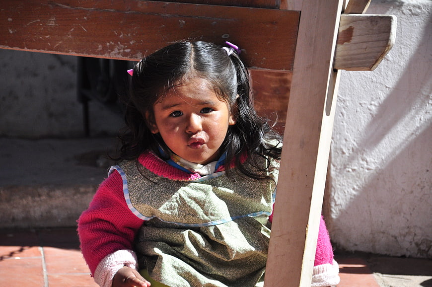 Cute young girl with pigtails sitting on wooden chair