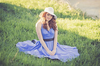 Young woman in blue polka dot dress sitting in grass