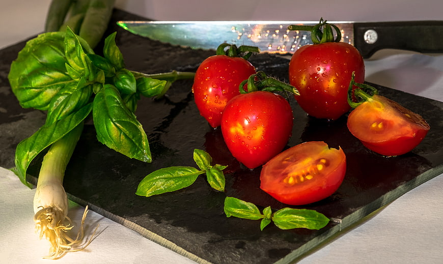 Fresh tomatoes and basil on a black slate board with knife