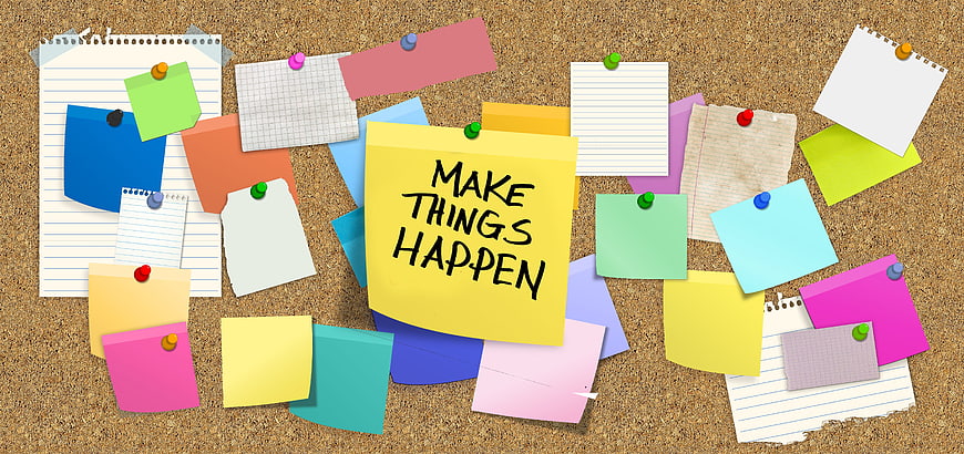 Cork board with colorful sticky notes and motivational quote
