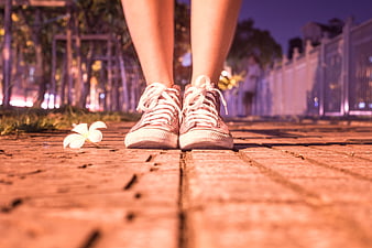Low angle shot of sneakers and flower on brick path at night