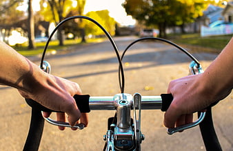 First Person View of Hands on Bicycle Handlebars in Autumn
