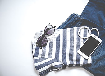 Flat lay of striped t-shirt, jeans, sunglasses, and smartphone