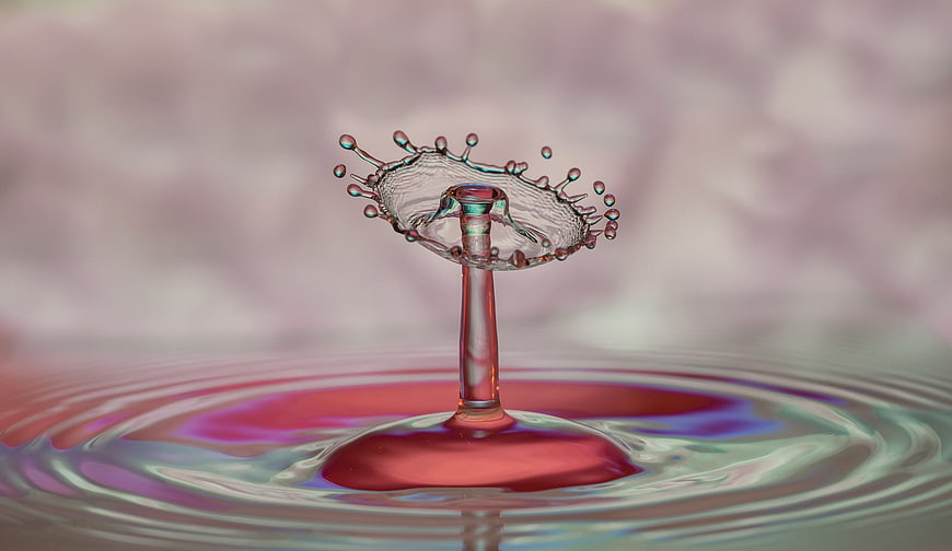 Macro water drop splash with colorful iridescent ripples