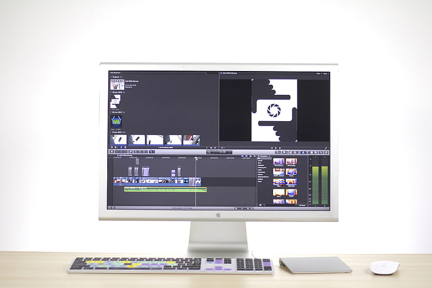 Apple iMac with video editing software on wooden desk