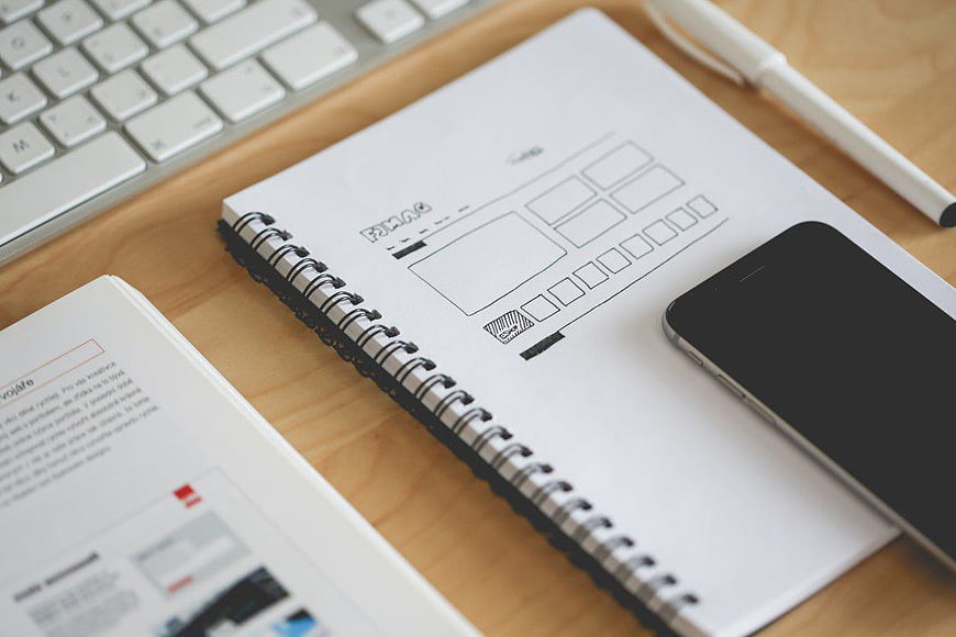 UX Wireframe Sketch on Notebook with Smartphone and Keyboard