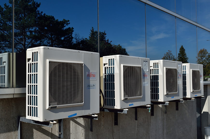Row of white Fujitsu air conditioning units on concrete wall