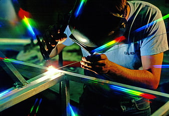 Welder working on metal frame with colorful light effects