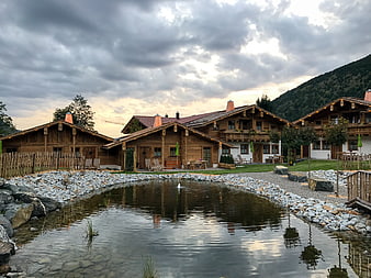 Traditional wooden chalets with pond and mountain backdrop